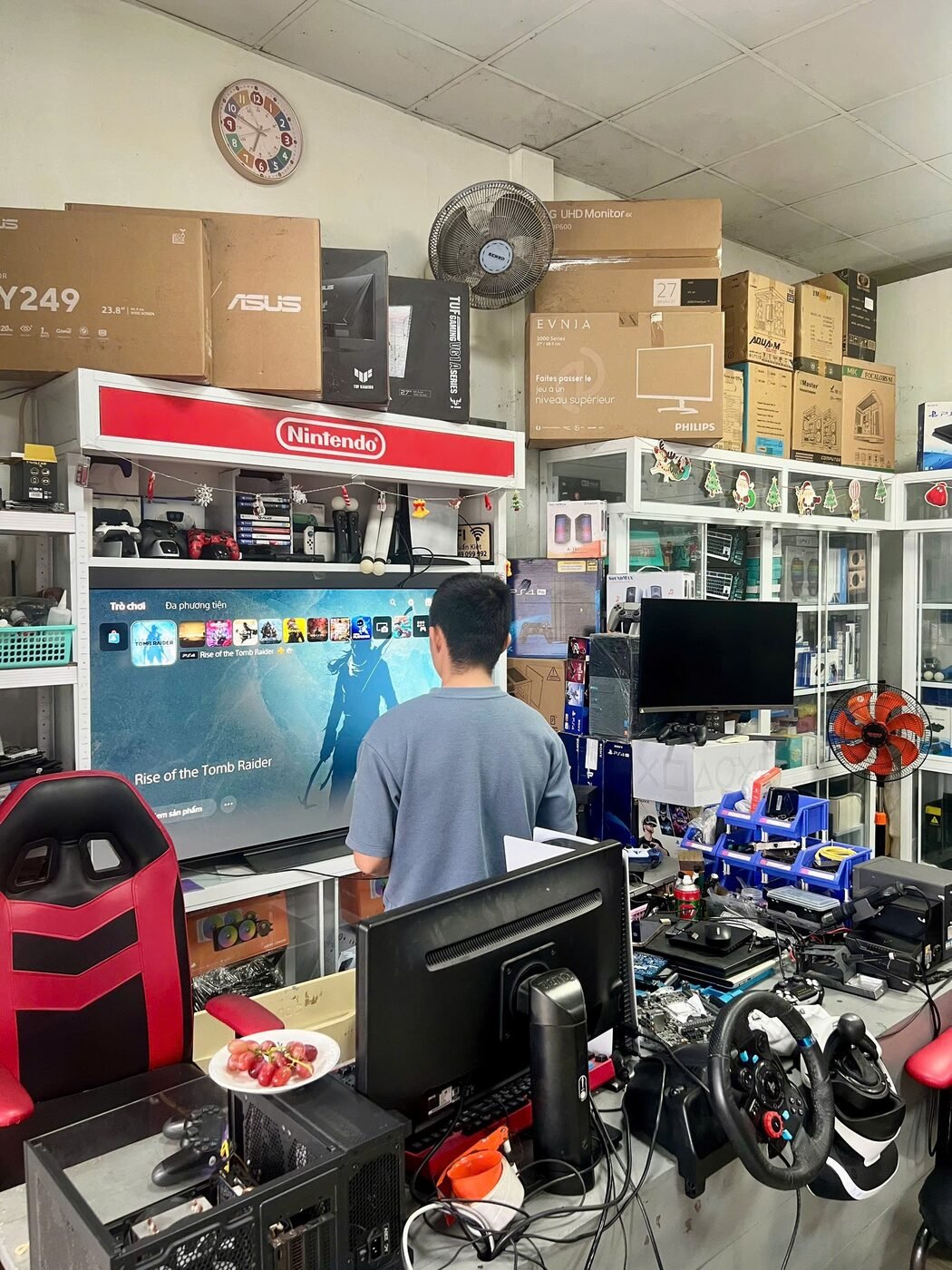 Khu vực test máy PS4, PS5 trong cửa hàng Hóng Game Store với TV lớn, kệ Nintendo và tủ trưng bày phụ kiện