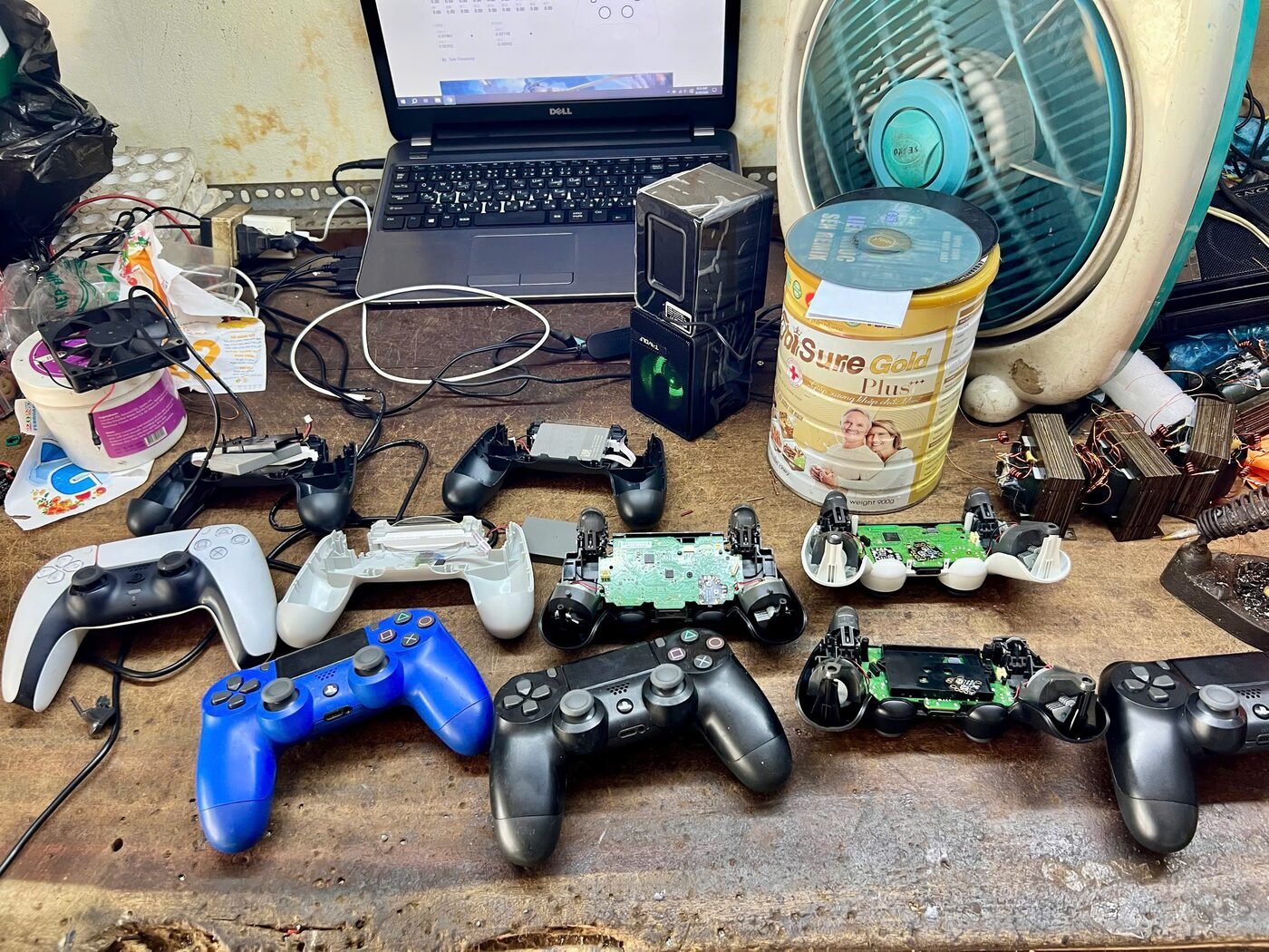 Nhiều tay cầm PS4 và PS5 đang được tháo rời để sửa trên bàn kỹ thuật của Hóng Game Store Cần Thơ